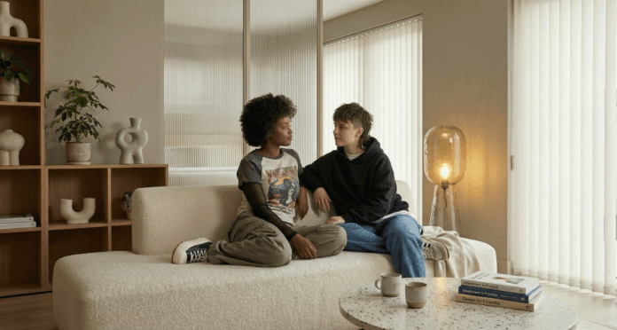 Two partners sit in calm eye contact on a softly lit sofa, their relaxed, respectful posture symbolizing emotional safety in relationships the trust, mindfulness, and presence that form true intimacy.