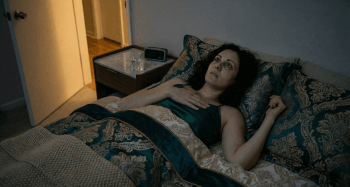 Middle Eastern woman lying in dark bedroom with eyes wide open showing anxiety-driven insomnia central to sleep hygiene for anxious adults